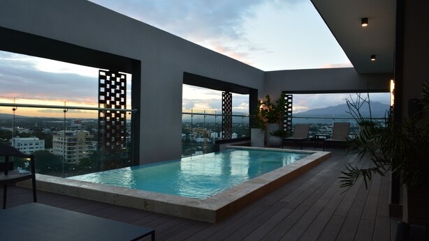 Una piscina a sfioro sulla terrazza con vista sulla città, architettura moderna e area relax all'aperto.