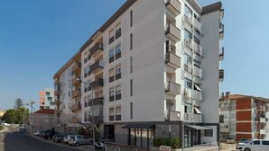 Un immeuble résidentiel à plusieurs étages, doté de balcons, d’une entrée couverte et d’un espace de stationnement.