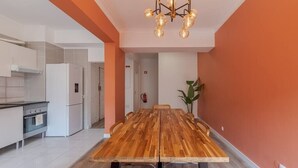 Une cuisine moderne avec des appareils électroménagers blancs, une table à manger en bois et un lustre.