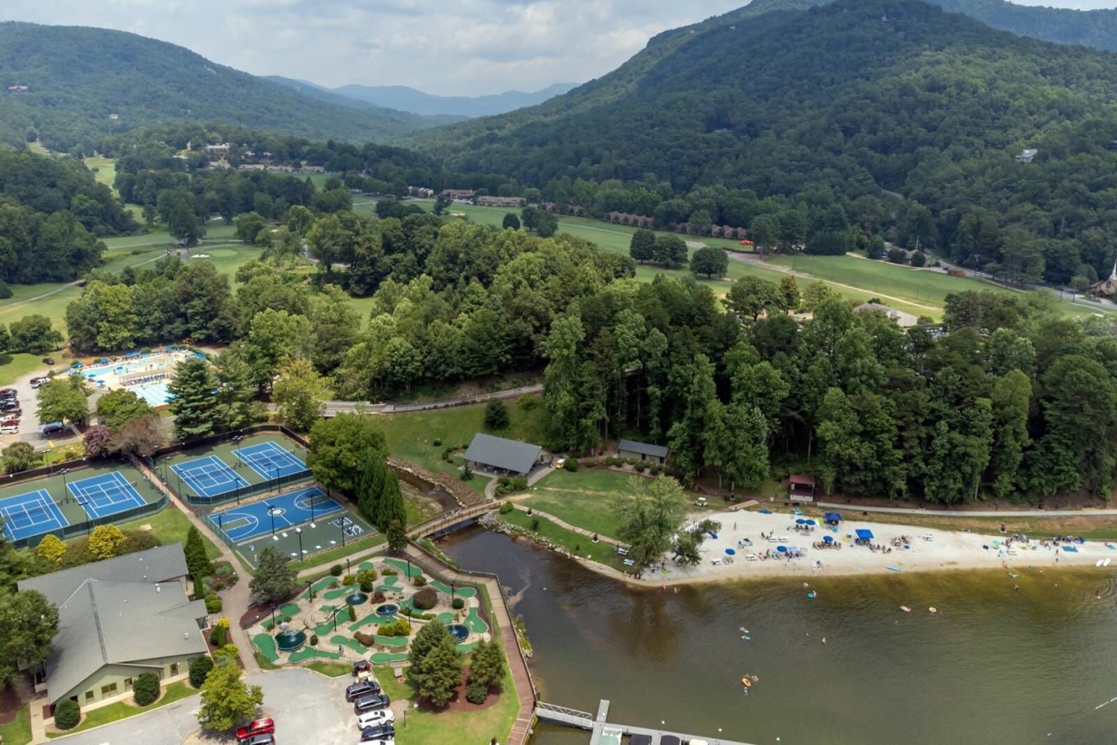 A golf course with multiple green areas and a lake.