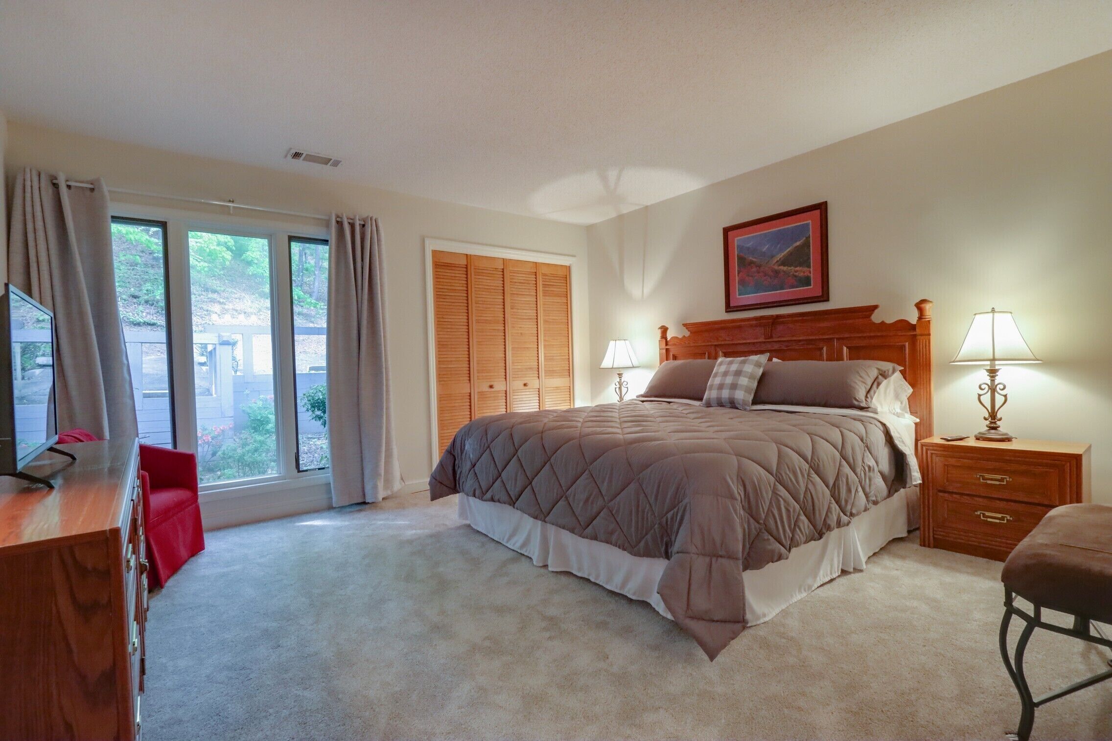 A bedroom with a bed, bedside tables, a desk, and a chair.
