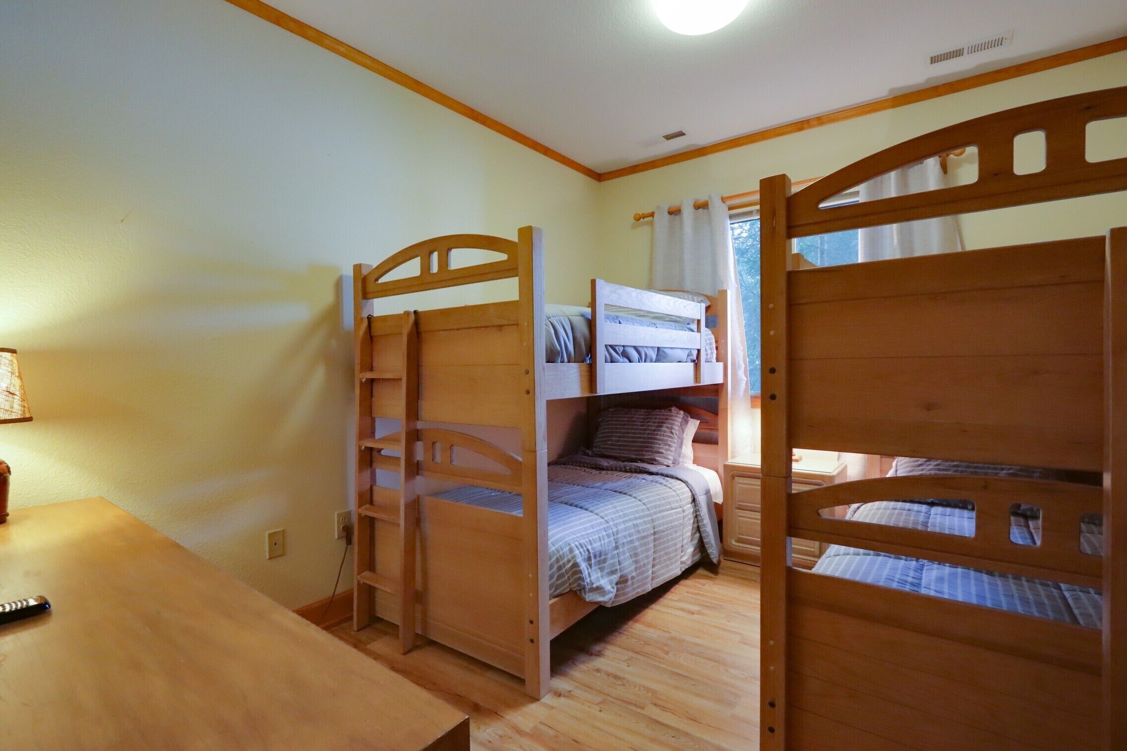 A bunk bed room with a wooden table and a lamp.
