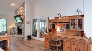 Un salon spacieux avec une cheminée en pierre, des meubles en bois et un téléviseur fixé au mur.
