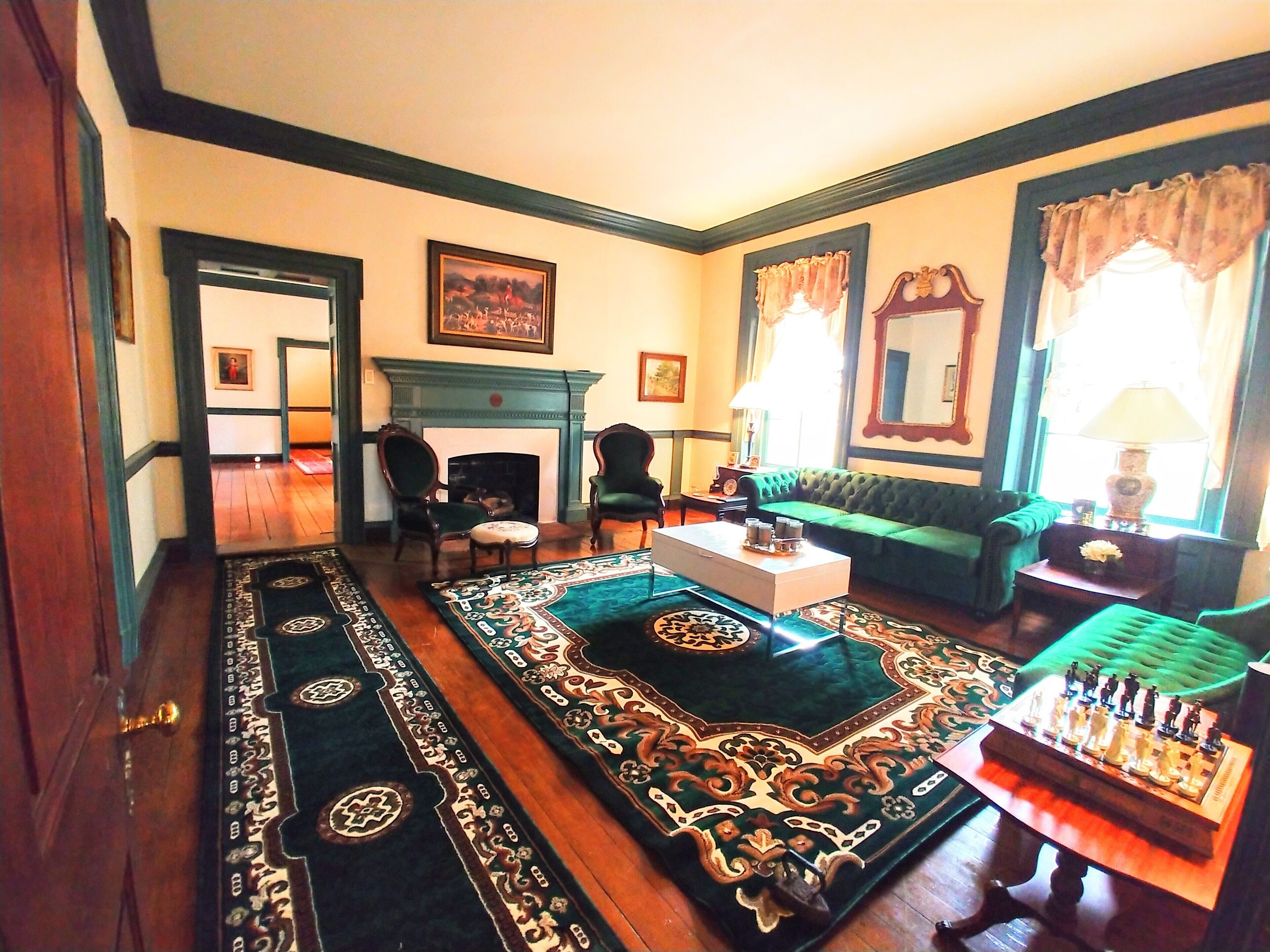 A traditional living room with a fireplace, green sofa, and a chessboard.