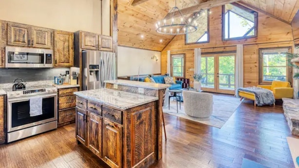 Une cuisine spacieuse avec des meubles en bois, un grand îlot central et un coin repas comprenant un canapé bleu et des chaises jaunes.