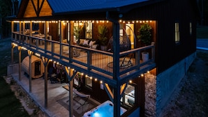 Une cabane en bois dotée d’une terrasse couverte, d’un bain à remous et de guirlandes lumineuses.