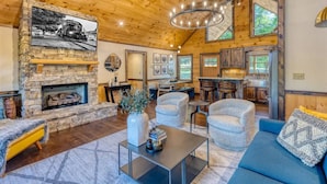 Un salon spacieux doté d’une cheminée en pierre, de sièges confortables et d’un coin repas avec des meubles en bois.