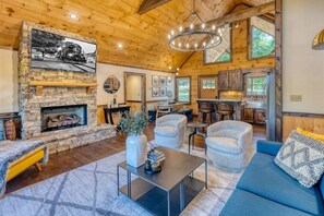 Relax in a spacious living area with a stone fireplace, comfortable seating, and a mounted TV.
