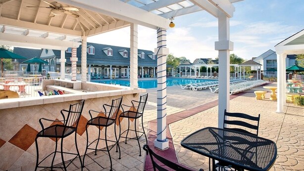 Ein überdachter Außenbereich mit Pool, Bar und Sitzgelegenheiten.