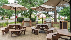 Eine Terrasse im Freien mit Picknicktischen und Grillanlagen.
