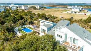 Una zona residencial costera con casas modernas, una piscina y vista al océano.