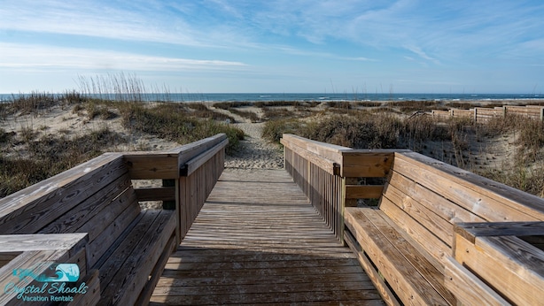Un muelle de madera que conduce a la playa, con vista despejada al océano.
