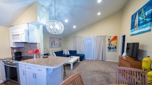 Un espacio habitable compacto con kitchenette, comedor, sofá y televisor.