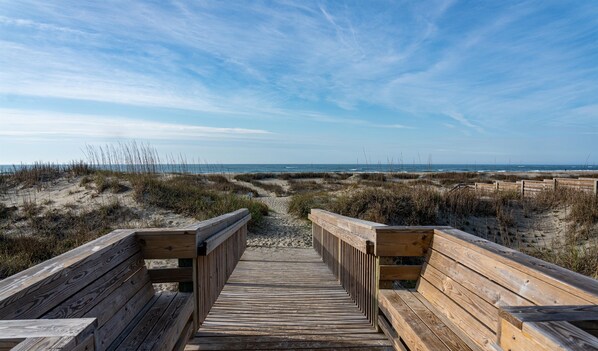 Une promenade en bois qui mène à la plage et offre une vue dégagée sur l’océan.
