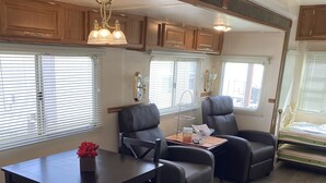 A compact RV interior with a dining area, two seating options, and a small kitchenette.