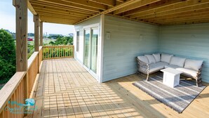 Eine überdachte Terrasse mit einem weißen Sofa und einem kleinen Tisch, umgeben von einem hölzernen Geländer.