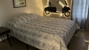 Ein Hotelzimmer mit einem Bett, einem gerahmten Bild an der Wand und einer wandmontierten Leuchte in Golfwagen-Form.