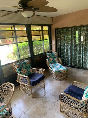Relax in this serene room with a high ceiling, ceiling fan, and comfortable wicker chairs.
