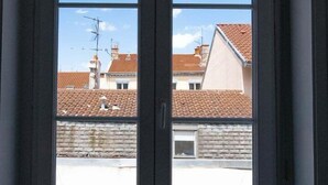 Uma porta dupla com vista clara para uma área residencial, incluindo casas e telhados cerâmicos.