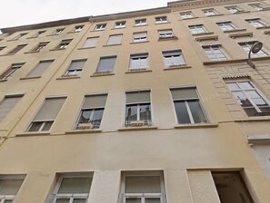 A multi-story building with a beige facade, multiple windows, and a visible entrance at the ground level.