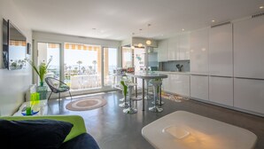 A modern kitchen with a dining area, large windows, and a view of the outdoors.
