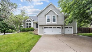 A two-story house with a garage, a driveway, and a well-maintained lawn. - Spacious 5-Bed Home with Pool in Overland Par! 27 (Overland Park)