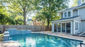 A backyard swimming pool with a tiled deck, a covered patio, and a wooden fence. - Spacious 5-Bed Home with Pool in Overland Par! 27 (Overland Park)
