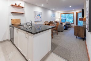 A modern kitchen with a central island, a dining area with a sofa and chairs, and artwork on the walls.