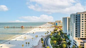 A beachside hotel with a long sandy beach, a pier, and modern buildings. - Wyndham Clearwater Beach Resort - 4 Bedroom (Clearwater Beach)