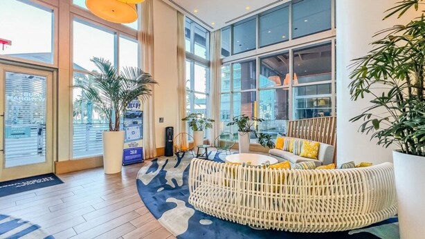 A spacious lobby with large windows, a central seating area with a woven chair, and potted plants. - Wyndham Clearwater Beach Resort - 4 Bedroom (Clearwater Beach)