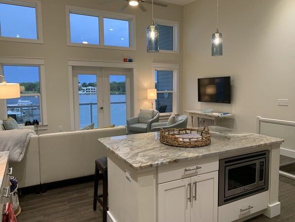A modern kitchen with a large island, built-in appliances, and a TV mounted on the wall.
