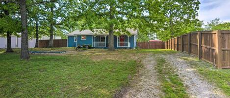A backyard with a blue house, a wooden fence, and a gravel path.