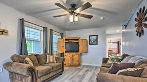 A living room with two sofas, a ceiling fan, and a wooden entertainment unit. - Table Rock Lake Retreat < 1 Mi to Boat Launch (Golden)