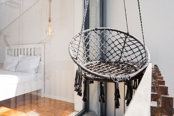 Una silla colgante de macramé en una habitación con cama y ventana.