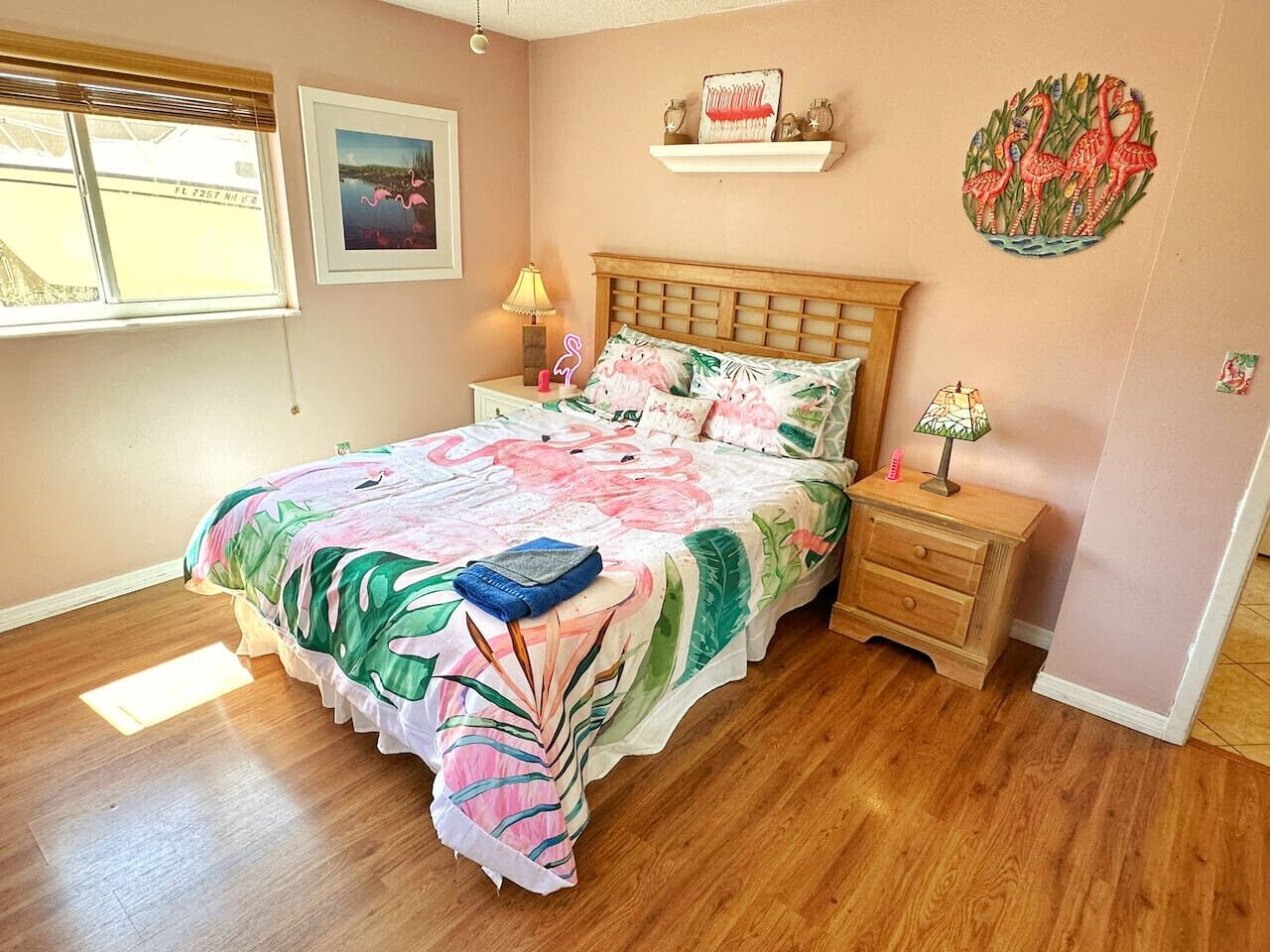 Un dormitorio con una cama de madera, una mesita de noche, una lámpara y una repisa en la pared con objetos decorativos.