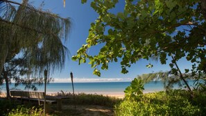 A beach with a bench, clear sky, and a view of the ocean.