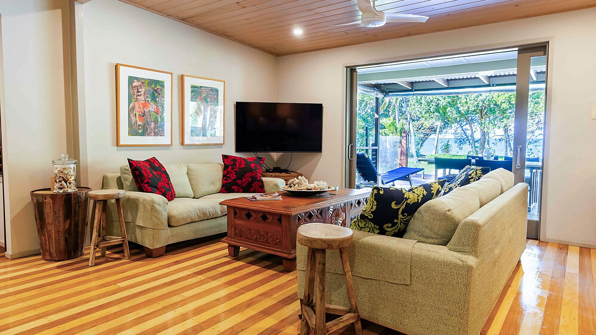 Sala de estar con piso de madera, dos sofás, una mesa de centro, televisor y vista al exterior.