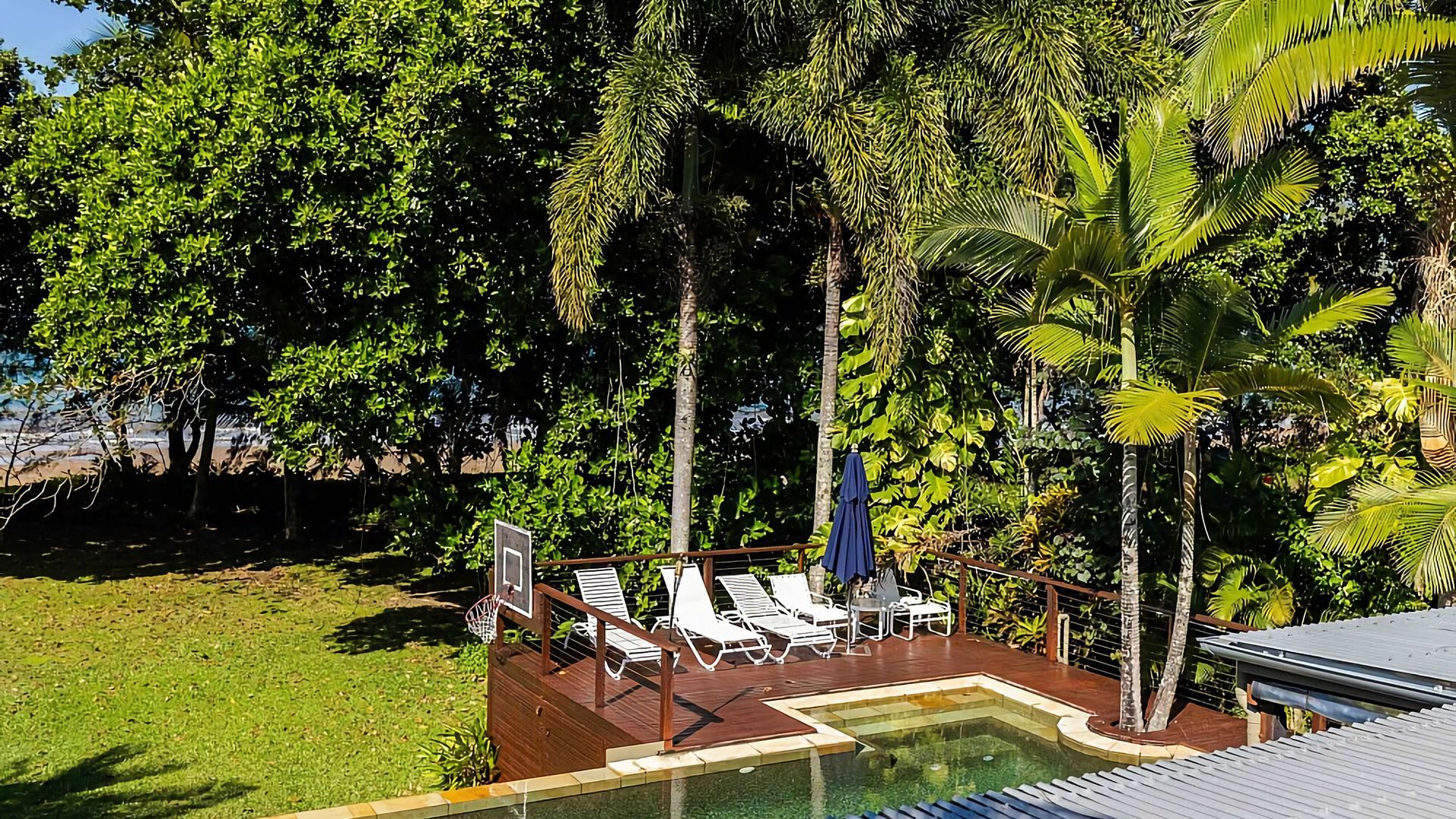 A pool area with lounge chairs and a basketball hoop.