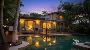 A modern house with a swimming pool, outdoor seating, and a staircase leading to the upper level.