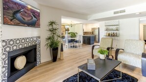 Ein modernes Wohnzimmer mit Kamin, Essbereich und einer Küche im Hintergrund.