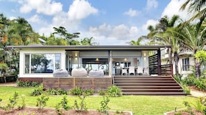 A modern house with a covered patio, outdoor seating, and a staircase leading to the entrance. - Ripples on the Beach (Mission Beach)