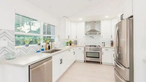 A modern kitchen with white cabinetry, a stainless steel refrigerator, and a built-in oven.