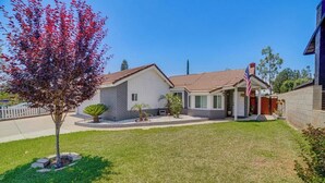 A single-story house with a front porch, a small front yard, and a tree with red leaves. - Spacious Studio with Private Entry (Moreno Valley)