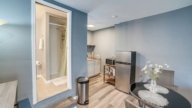 A modern kitchen with a refrigerator, microwave, and a dining area with a table and chairs. - Spacious Studio with Private Entry (Moreno Valley)