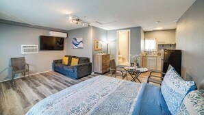 A modern hotel room with a large bed, a sofa, a dining table, and a kitchenette. - Spacious Studio with Private Entry (Moreno Valley)