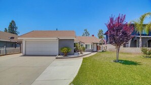 A residential street with houses, a well-maintained lawn, and a clear sky. - Spacious Studio with Private Entry (Moreno Valley)