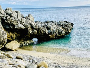 A rocky coastline with clear blue water and a sandy beach. - Detached cottage with an ocean view, 2 minutes from the beach – parking available. (Coccorino)