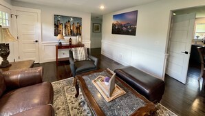 A living room with a sofa, a coffee table, and a fireplace. There is a painting on the wall and a door leading to another room. - Spacious 4 Bedroom House in Quiet Neighborhood, near Light Rail (Seattle)