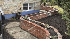 A house with a stone facade, a blue trim, and a brick garden bed with plants. - Spacious 4 Bedroom House in Quiet Neighborhood, near Light Rail (Seattle)