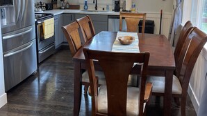 A modern kitchen with stainless steel appliances, a dining table with chairs, and a window with blinds. - Spacious 4 Bedroom House in Quiet Neighborhood, near Light Rail (Seattle)
